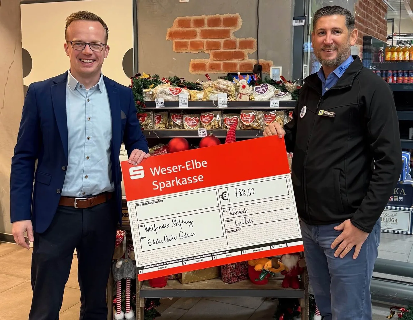 Andre Fricke und Artur Galwas mit dem Pfandbox-Jahresscheck 2025 über 788,93 Euro